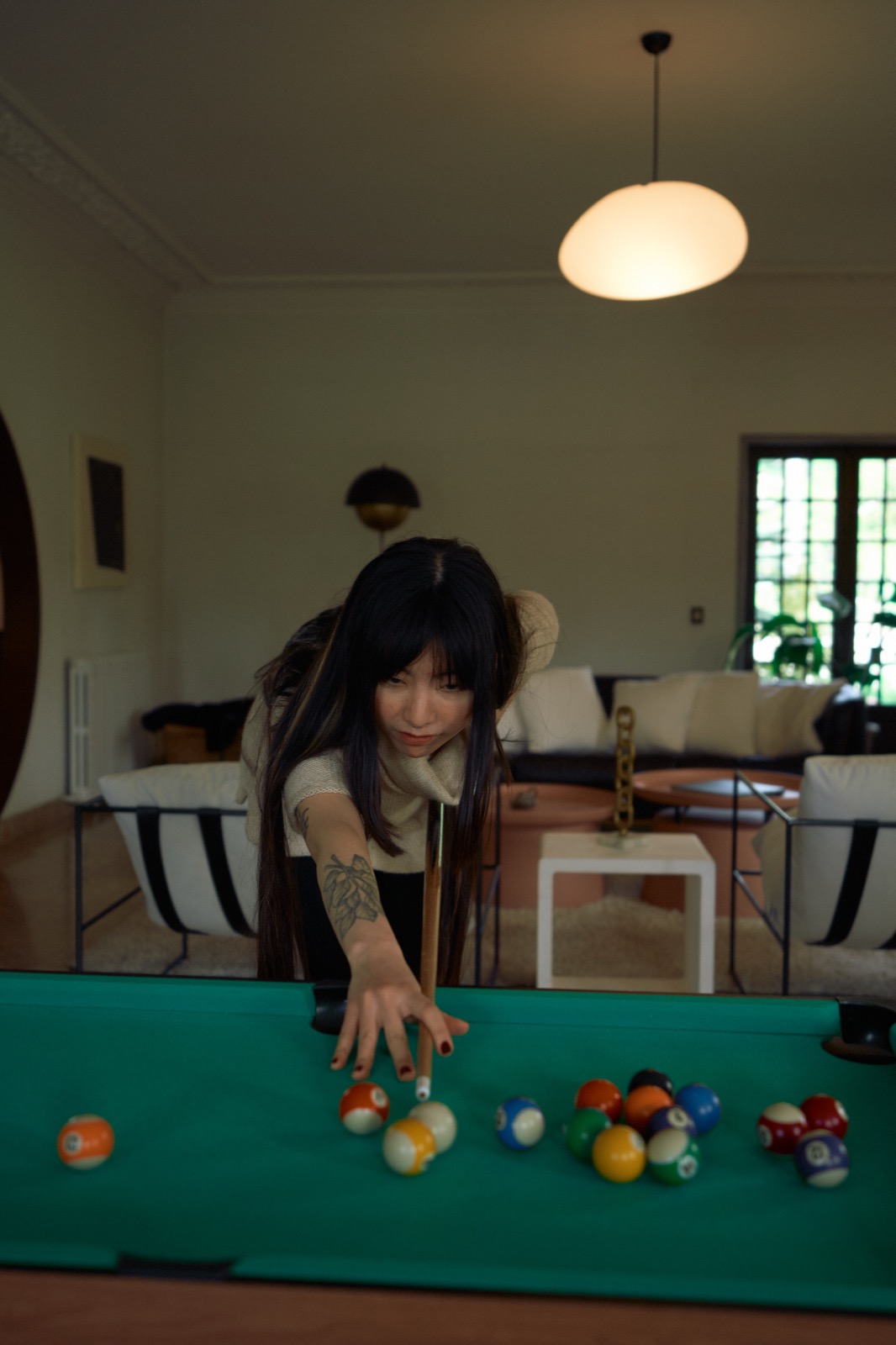 Someone lining up a shot on the pool table in the salon